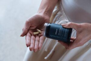 Vrouw schud SynTernals NRgize+ NAD+ booster supplementen uit pot