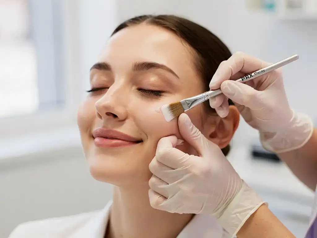 Vrouw met gesloten ogen ontvangt PRX-therapie behandeling met fijne applicator in witte kliniek met natuurlijk licht